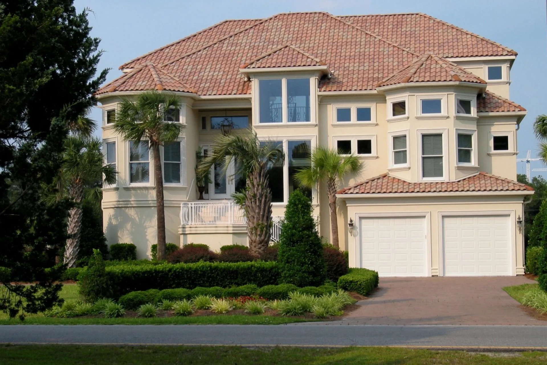 A large house with a driveway and bushes.