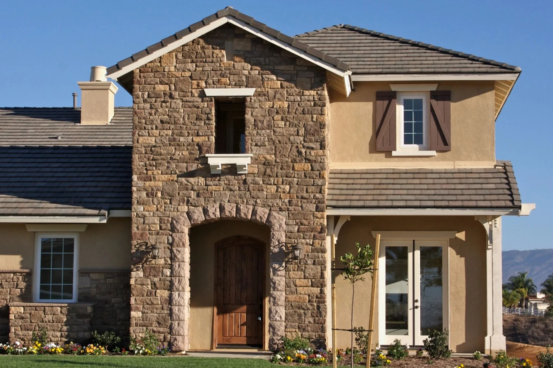 A house with a large stone wall and two windows.