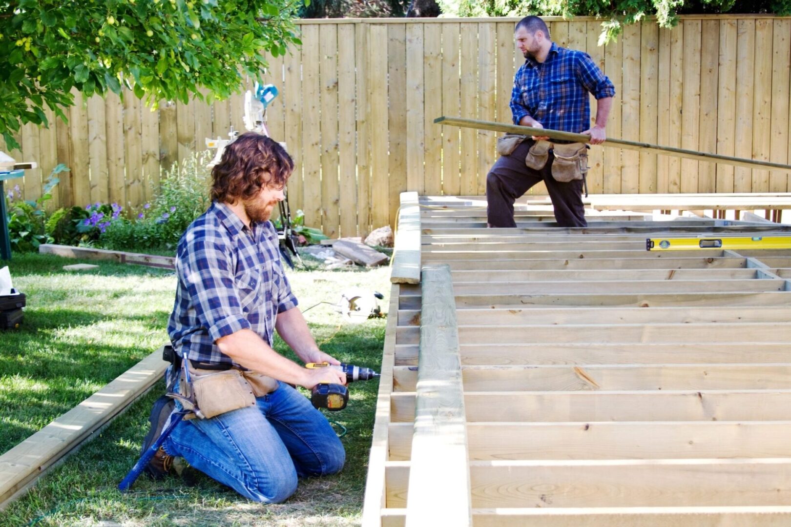 Two men working on a deck in the backyard.