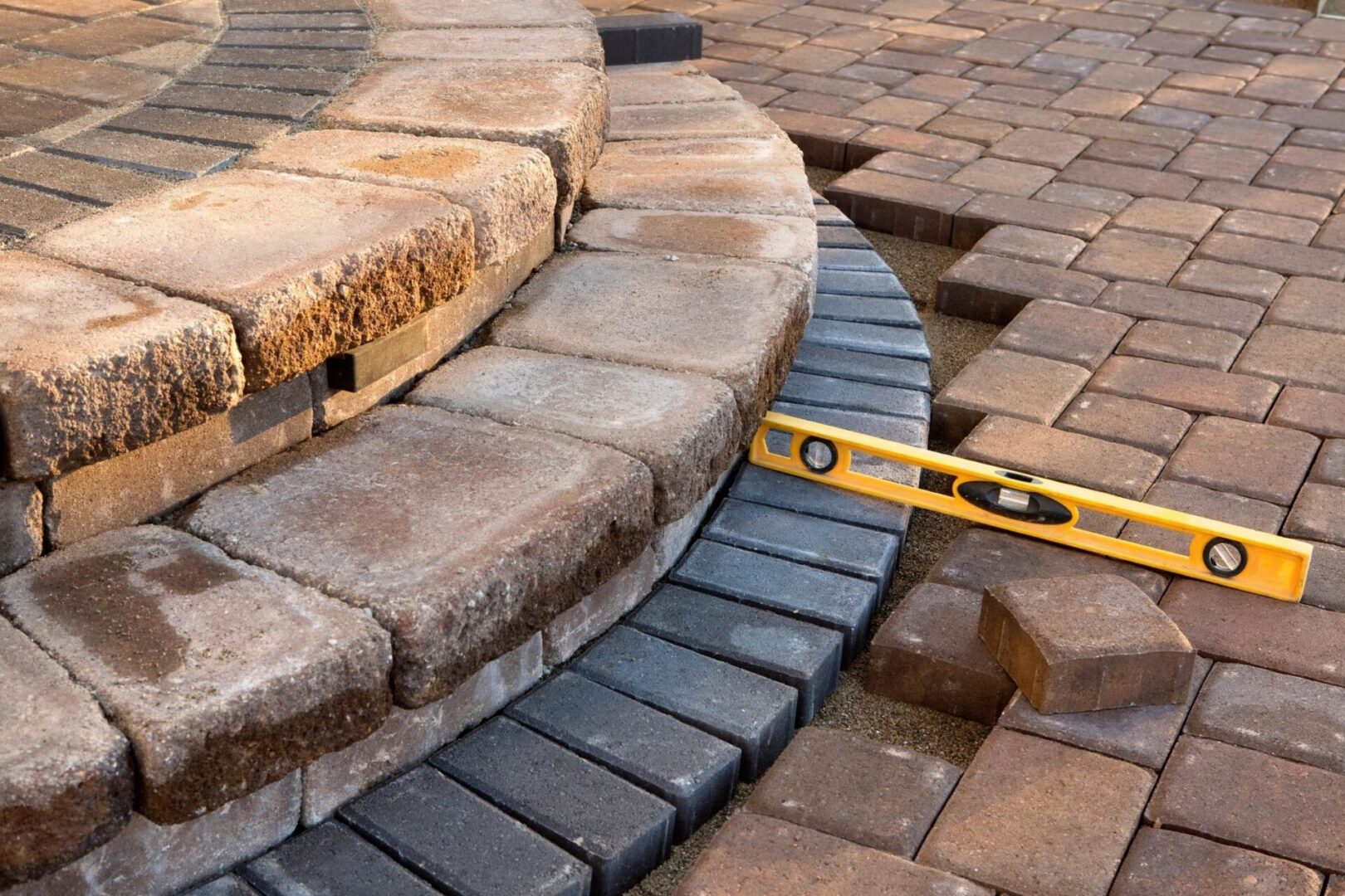 A yellow level sitting on top of a brick walkway.