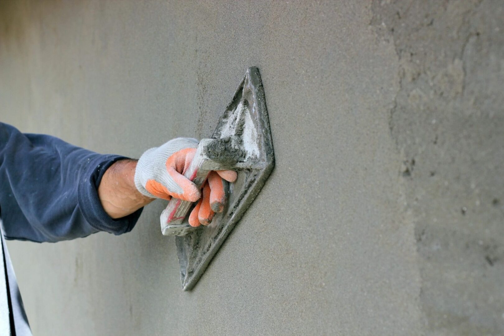 A person is holding a spatula and spreading it on the wall.