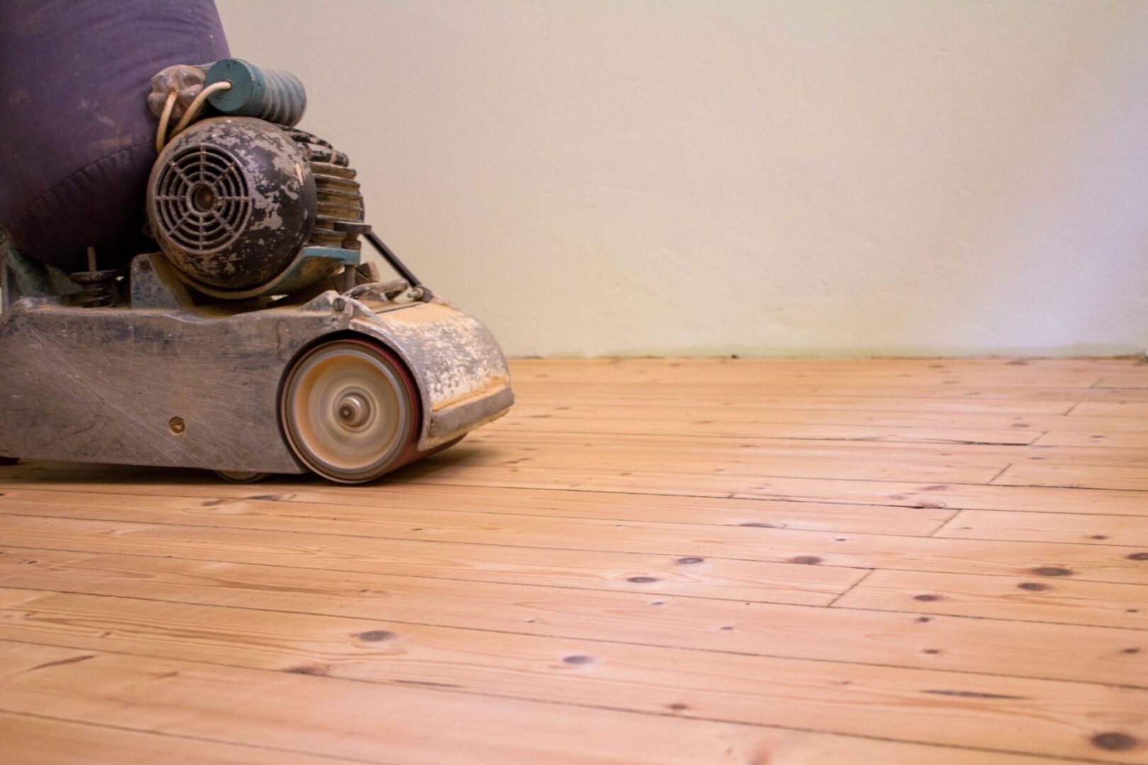 A person is using an electric mower to cut the floor.